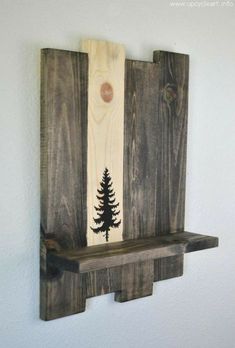 a wooden shelf with a pine tree painted on the front and bottom, hanging from a wall