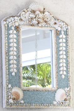 a mirror that is on the side of a wall with seashells around it