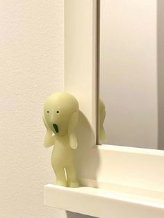 an elephant figurine sitting on the edge of a mirror