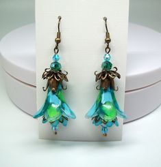 Green flower earrings, Boho earrings, Dangle & drop earrings. Hand painted and color sealed (permanent). Wonderful lime green, baby blue and turquoise trumpet flowers accompanied by turquoise mini-inner flowers with turquoise and green faceted crystal accent beads. Dressed up or down no matter the occasion these colorful floral statement earrings are sure to compliment you.  Earrings are lightweight and can be worn comfortably all day long. Gift for mom? Friendship gift for her? Coworker gift? B Green Flower Charm Drop Earrings, Blue Whimsical Dangle Flower Earrings, Whimsical Blue Dangle Flower Earrings, Green Dangle Flower Earrings For Gift, Bohemian Green Flower Charm Earrings, Unique Blue Flower Earrings With Ear Wire, Turquoise Flower-shaped Earrings With Flower Charm, Whimsical Blue Drop Earrings, Turquoise Earrings With Flower Charm