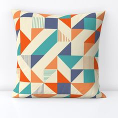 an orange, blue and white pillow with geometric designs on the front is sitting on a table