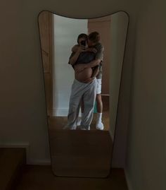 a man and woman standing in front of a mirror taking a selfie with their cell phone