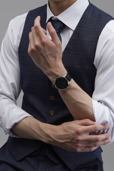 a man in a suit and tie is holding his hands together while wearing a watch