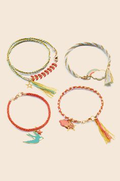 four bracelets with charms and tassels on them