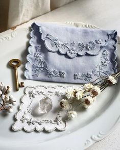 a white plate topped with flowers and a small purse next to an old skeleton key