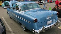 an old blue car is parked on the street