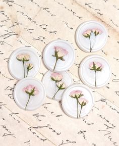 four white plates with pink flowers on them are sitting on a piece of parchment paper