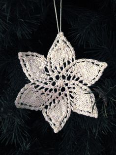 a white crocheted ornament hanging from a christmas tree in front of a black background