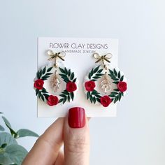 a pair of red roses and leaves are attached to earrings