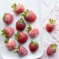 chocolate covered strawberries with sprinkles on a white plate next to pink napkins