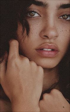 a woman with freckled hair and blue eyes is posing for the camera while holding her hand near her face