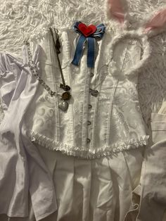 a white corset with blue ribbon and red heart on it sitting on a bed