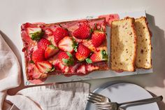 a piece of cake with strawberries on it next to a fork and napkins