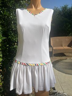 Here is a vintage 1970s polyester tennis dress. Following are the measurements.Bust 34",Waist 30",hips 36",Length measured from top of shoulder to bottom 29".Zips up the back. Pleated skirt. Colorful stripe trim around hip area and neck.In nice vintage condition.If you live overseas please email me before purchasing for mailing cost. Price quoted is for USA only. Please take special note of measurements. 1970s sizing was much smaller than today's standards. Tennis dresses were very short not like a regular dress. So please take special note of lengths V-neck Tennis Dress For Spring, Fitted Tennis Dress For Summer, White A-line Tennis Dress For Summer, Tennis Dresses, Spring 2025, Womens Sports, Tennis Dress, Vintage 1970s, Sports Women