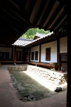 an empty courtyard with rocks and grass on the ground in front of a white building