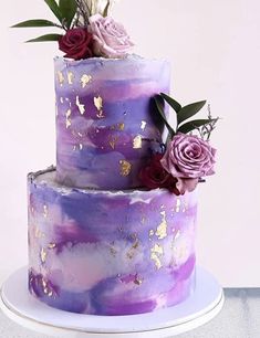 there is a three layer cake with purple and gold designs on it, decorated with flowers