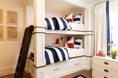 a bunk bed with blue and white striped pillows on it's bottom shelf next to a window