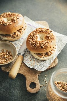 two bagels with sprinkles sit on top of a cutting board