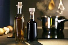 two bottles of olive oil sitting on a counter