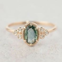 a ring with an oval green stone surrounded by small white diamonds on a gray background