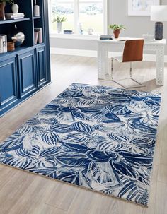 a blue and white area rug in a living room with a book shelf on the far wall