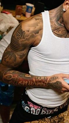 a man with many tattoos on his arm and chest holding a cell phone in his hand