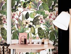 a desk with a lamp and wallpaper in the background that has tropical leaves on it