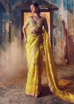 a woman in a yellow sari posing for the camera with her hands on her hips