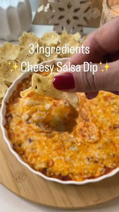 a hand dipping a tortilla chip into a bowl of cheesy salsa dip