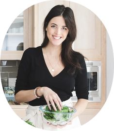 a woman holding a bowl filled with green vegetables