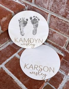 two personalized baby footprints are on the side of a brick wall