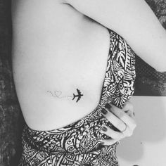 a black and white photo of a woman with a small airplane tattoo on her stomach