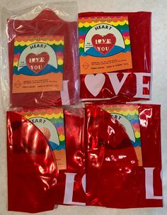 four red bags with hearts and i love you stickers on them sitting on a white surface