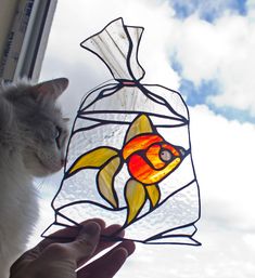 a cat is looking at a stained glass fish