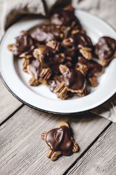 a white plate topped with chocolate covered cookies on top of a wooden table next to an apple