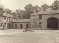 an old photo of a stone building with a fountain in the middle