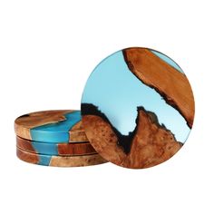 two round wooden coasters with blue and brown designs on the top one has a mountain in the background