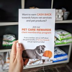 a person holding up a sign with a dog on it in front of some shelves