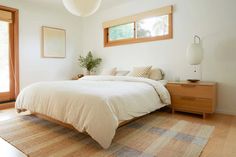 a bedroom with a bed, nightstands and two windows in the wall above it