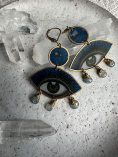 Blue mystic eye print set in resin. Blue zircon gemstone drops. Brass hardwear and leaver back claps. Please message me with any questions. Mystical Blue Round Jewelry, Spiritual Blue Gold-plated Jewelry, Blue Brass Amulet Jewelry, Blue Spiritual Collectible Jewelry, Mystical Blue Pendant Jewelry, Mystic Eye, Zircon Gemstone, Eye Print, Blue Zircon