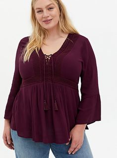 This whimsical babydoll features a V-neck with lace-up detail, bell sleeves, and additional crochet details.   Gauze woven fabric. V-neck; lace-up with tassel ends. 3/4 sleeves; bell cuffs. Stretch waist. Crochet details. CONTENT + CARE Rayon. Dry clean only. Imported plus size tops. SIZE + FIT Model is 5'10”, size 1. Size 2 measures 31” from shoulder. The best plus size women's burgundy purple gauze lace-up babydoll & empire waist tops in winetasting made of gauze. Torrid is your desti Empire Waist Tops, Chiffon Tunic, Fitted Wedding Dress, Cute Blouses, Lace Inset, Feel Pretty, Crochet Details, Plus Size Womens Clothing, Crochet Trim