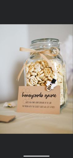 a glass jar filled with lots of food on top of a wooden table next to a sign