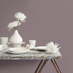 a table topped with white dishes and vases