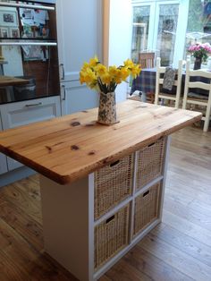 a vase with yellow flowers sitting on top of a wooden counter in a kitchen next to an oven