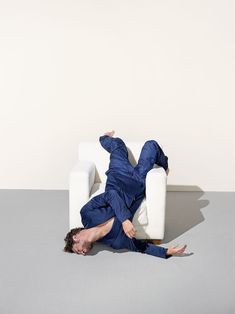 a man laying on the floor in front of a white couch with his legs spread out