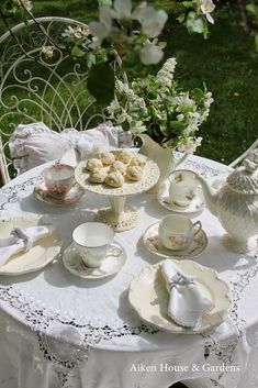 a table topped with plates and cups filled with tea set on top of a white table cloth