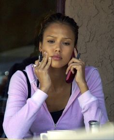 a woman sitting at a table talking on her cell phone