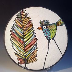 a colorful bird painted on a white plate