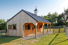 a small wooden building with a steeple on the top and two stalls in front