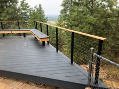 a wooden bench sitting on top of a metal rail next to a tree filled forest